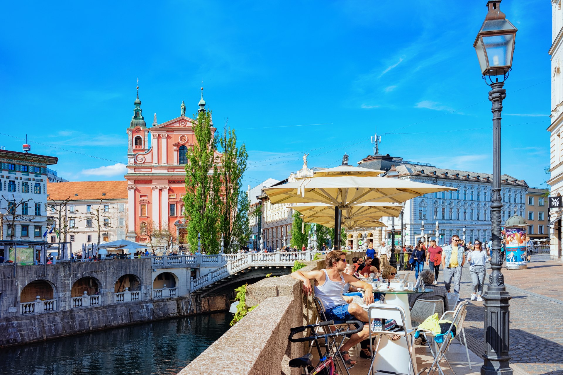Menschen in einem Straßencafé an den Drei Brücken an der Ljubljanica in Ljubljana